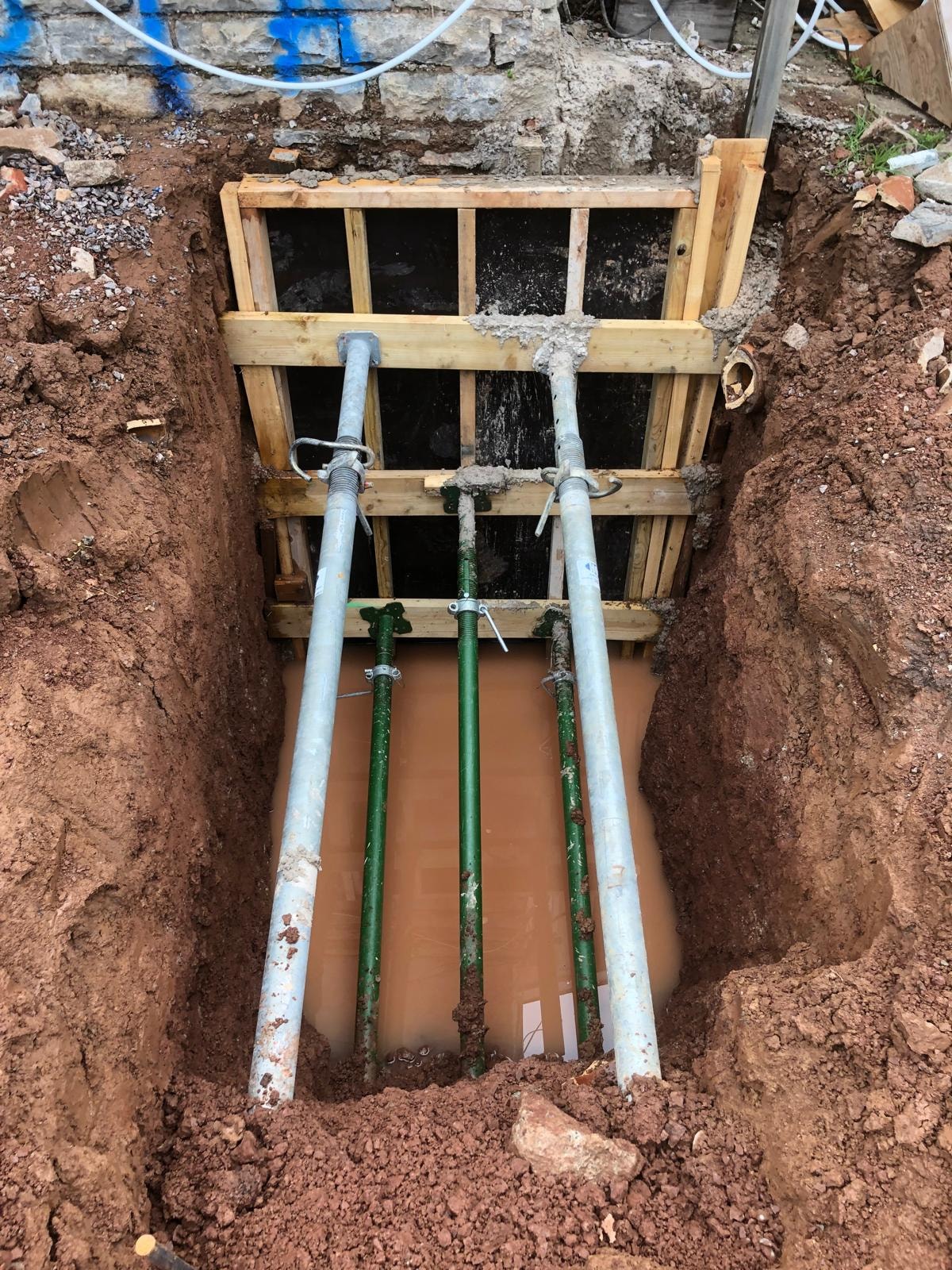 Supported trench work during underpinning construction